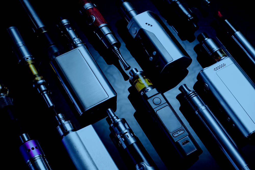 Various e-cigarette devices lined up diagonally on a dark table